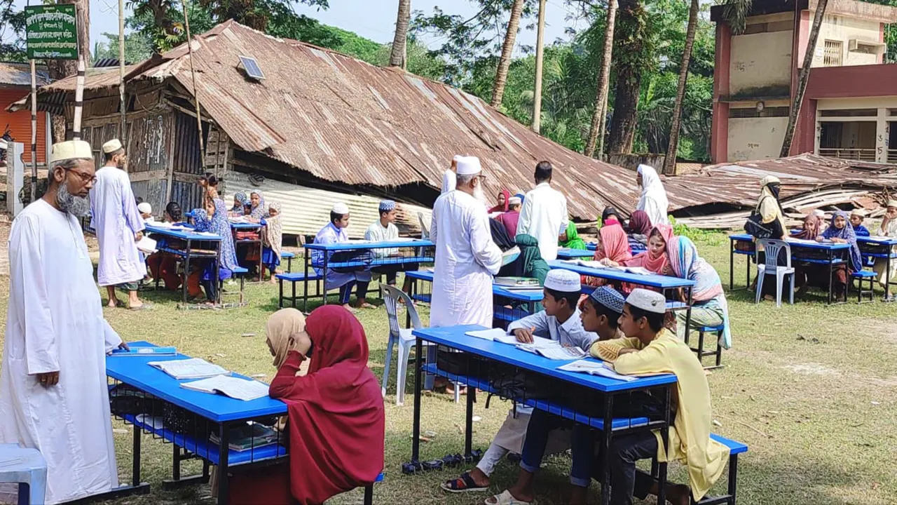 ঘূর্ণিঝড়ে রিমালে ভান্ডারিয়ায় রাজপাশা দারুশ শরিয়াত দাখিল মাদ্রাসার ভবন ভেঙে পড়ায় মাঠে পাঠদান চলছে শিক্ষার্থীদের। ছবি : কালবেলা