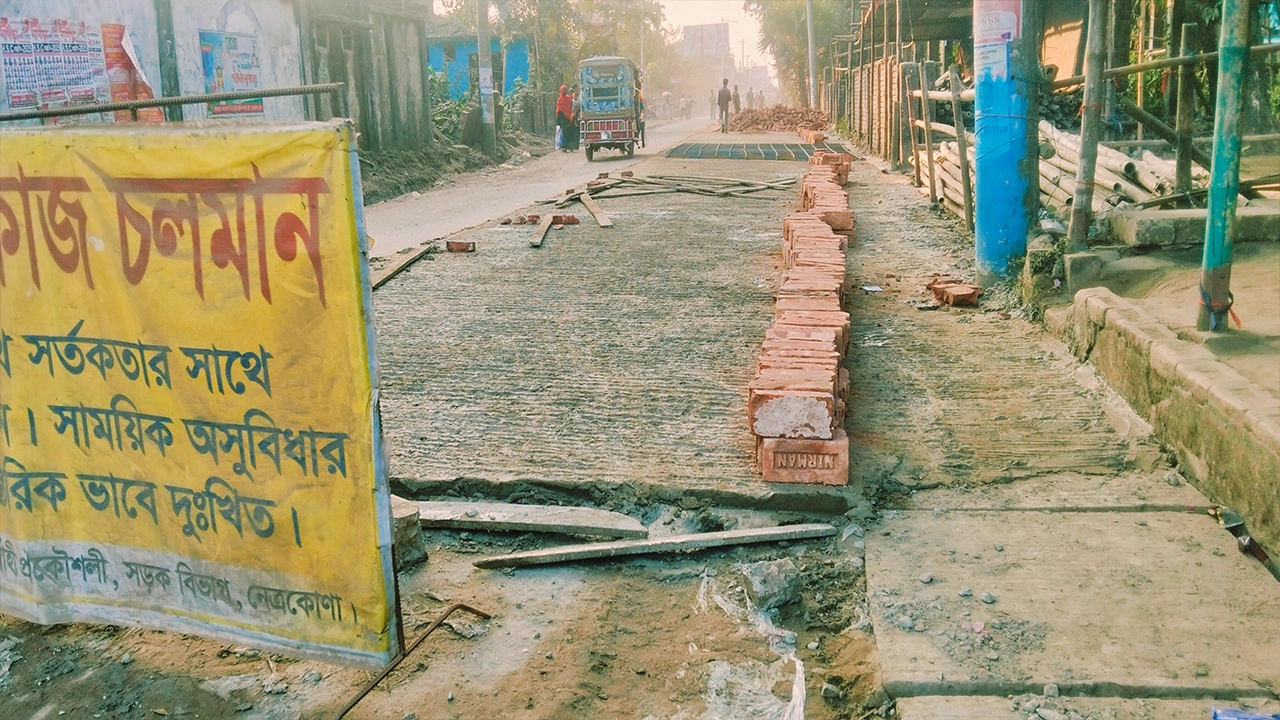 নেত্রকোনায় ড্রেনের ওপর ঢালাই দিয়ে রাস্তা বৃদ্ধির কাজ চলছে। ছবি : কালবেলা